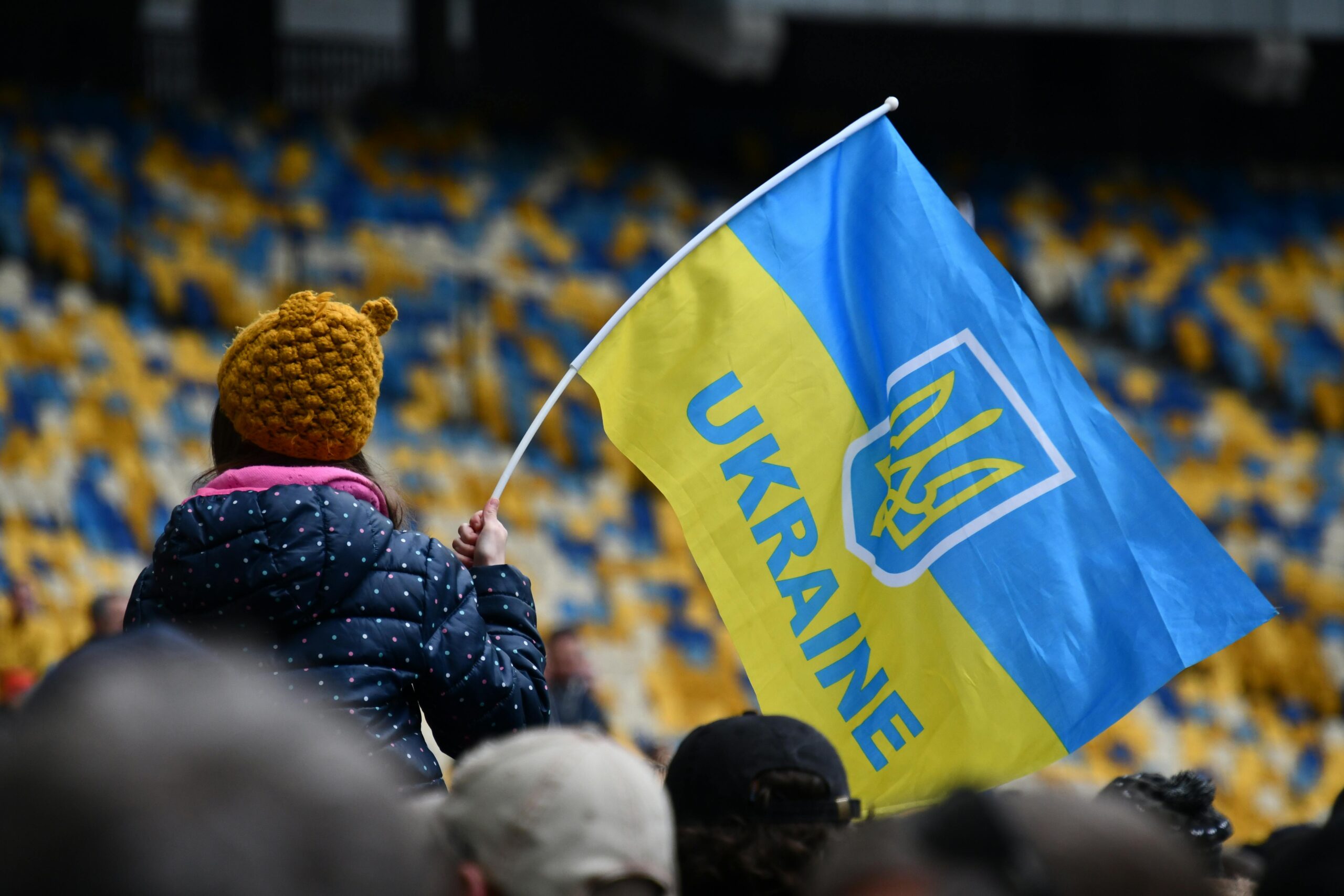 A child waving the Ukrainian flag in a stadium in Kiev, showcasing patriotism and unity.